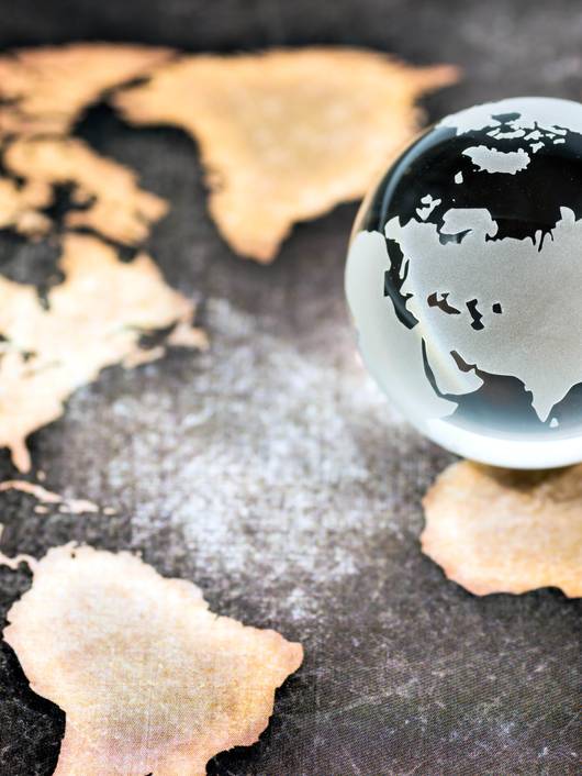 A glass globe centered on Europe and Africa rests on a vintage map.