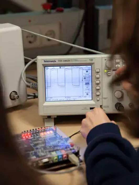 Una persona está utilizando un osciloscopio para analizar una señal electrónica.