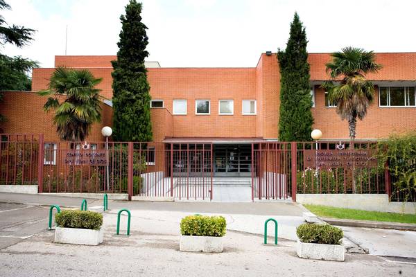 A modern school building with a gated entrance and surrounding greenery.