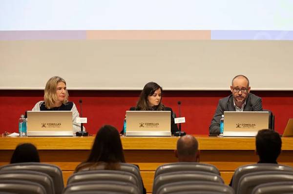 Una mesa de conferencia con tres ponentes discutiendo frente a una audiencia.
