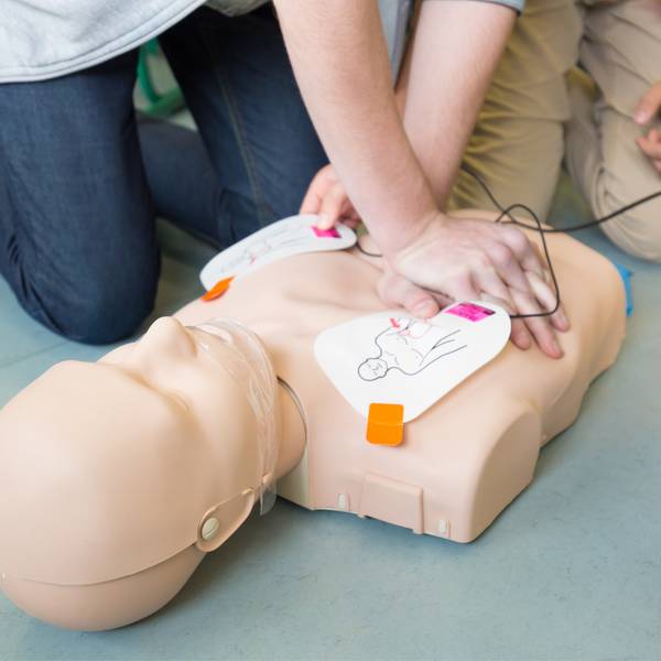 Dos personas están realizando maniobras de reanimación cardiopulmonar sobre un maniquí.