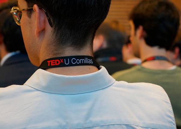 Un grupo de personas en un evento, destacando la espalda de alguien con un distintivo de TEDx U Comillas.