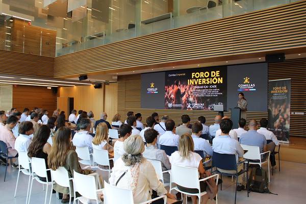 Una conferencia sobre inversión con un ponente en un escenario y una audiencia atenta en un salón moderno.