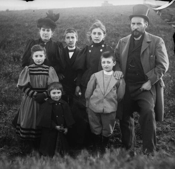 Fotografía en blanco y negro de una familia de siete miembros posando en un campo al aire libre.