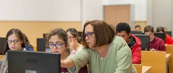 Una profesora ayuda a sus estudiantes en un aula de informática.