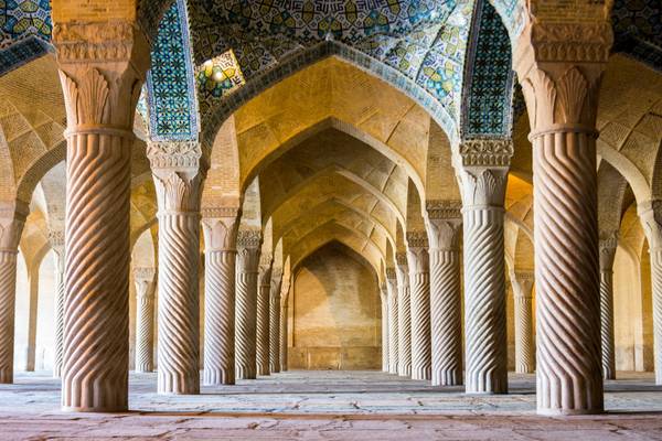 Un interior de columnas con arcos en un edificio monumental que destaca por su arquitectura islámica.
