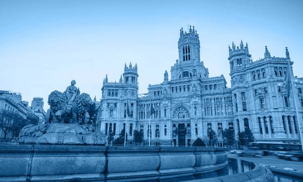 Vista del Palacio de Cibeles en Madrid con una fuente en primer plano.