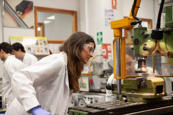 Una estudiante trabaja en un laboratorio utilizando una máquina herramienta.