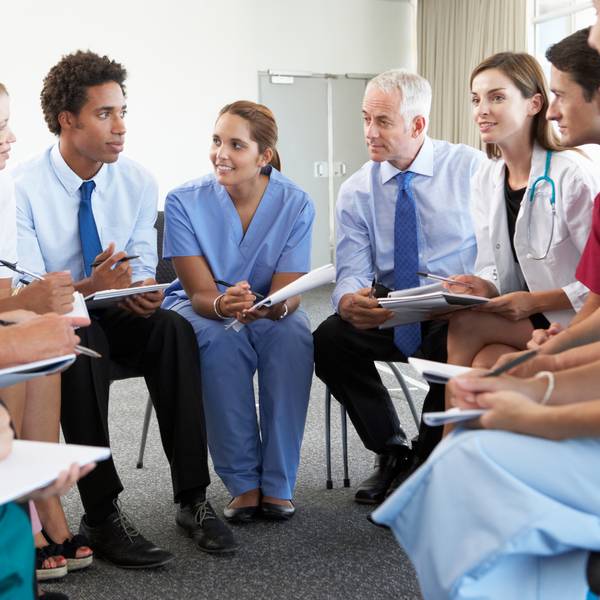 A group of diverse medical professionals, including doctors and nurses, engaged in a discussion while sitting in a circle.