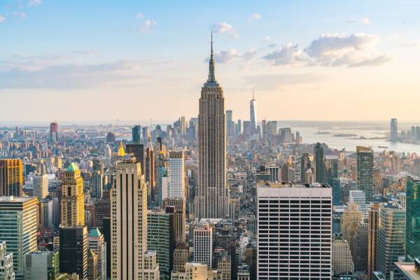 La imagen muestra el icónico edificio Empire State en Nueva York, con un horizonte urbano al fondo.
