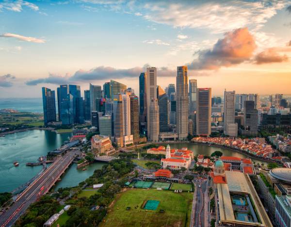 Una vista panorámica de la ciudad de Singapur al atardecer con rascacielos y un río.