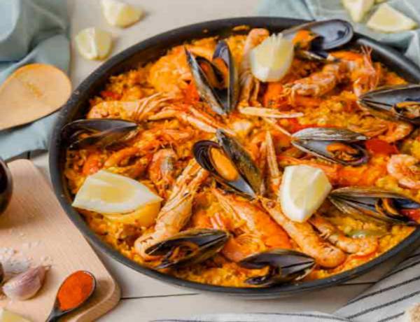 Un plato de paella con mariscos, camarones y limón.