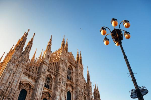 La imagen muestra la majestuosa fachada de una catedral con un farola en primer plano, bajo un cielo despejado.