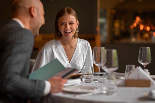 Una pareja sonríe y conversa en un elegante restaurante.