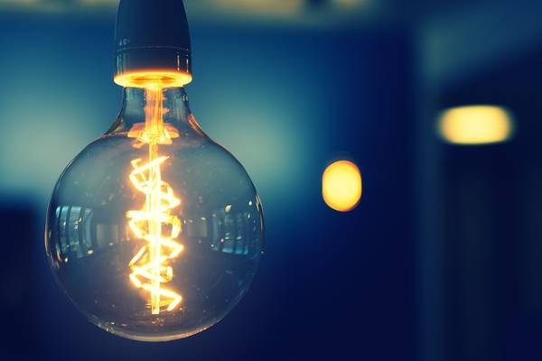 Una bombilla de luz incandescente emitiendo un brillo cálido en un fondo desenfocado.