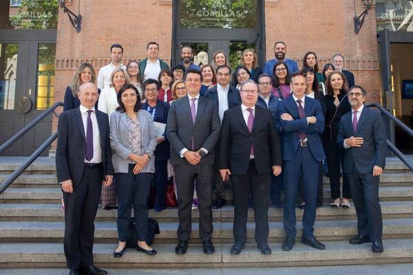 A group of business professionals posing for a photo on the steps of a building.