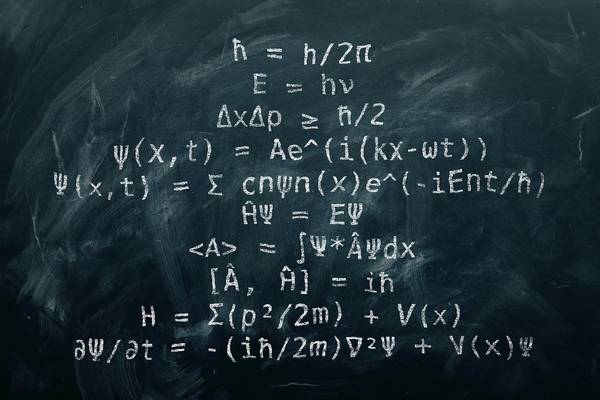 La imagen muestra fórmulas y ecuaciones relacionadas con la mecánica cuántica escritas en una pizarra.