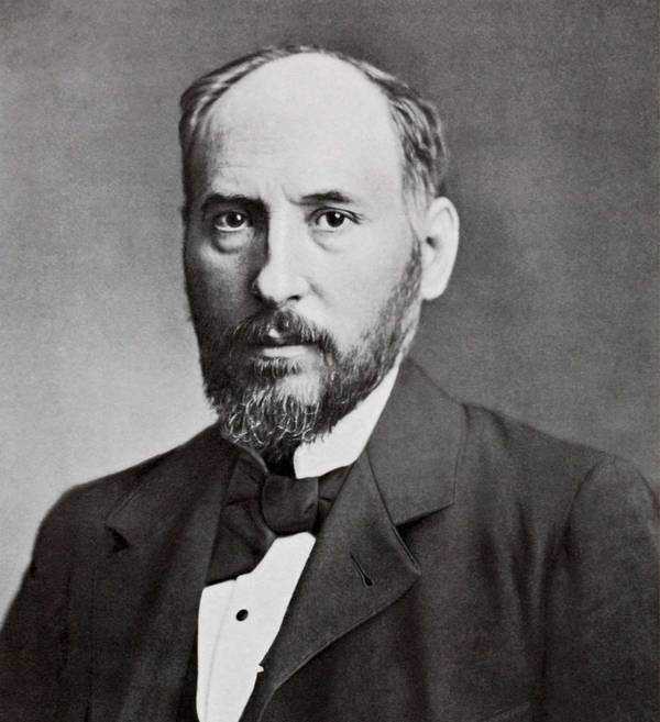 Retrato en blanco y negro de un hombre con barba, vistiendo una chaqueta formal.