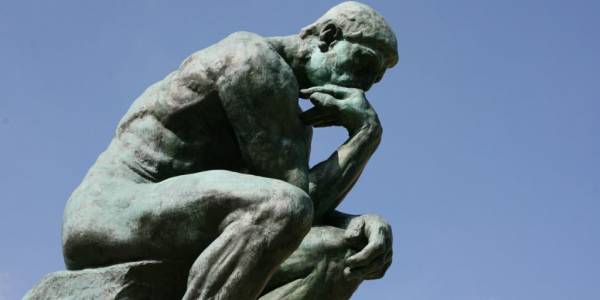 Una escultura de un hombre pensativo en una pose reflexiva.