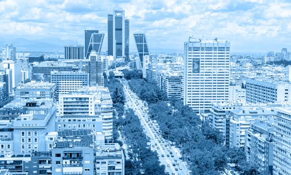 Vista panorámica de una ciudad moderna con edificios altos y una avenida arbolada.