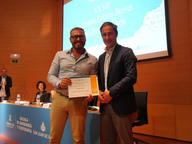 Un hombre recibe un premio en una ceremonia que se lleva a cabo en un auditorio.