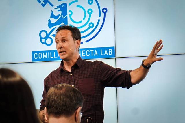 Un orador explica un tema con entusiasmo frente a una audiencia en un laboratorio de innovación.