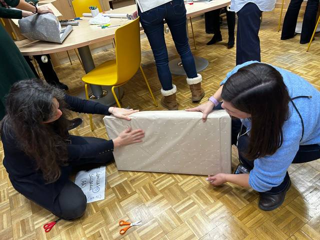 Dos personas están envolviendo un regalo en un ambiente de trabajo.