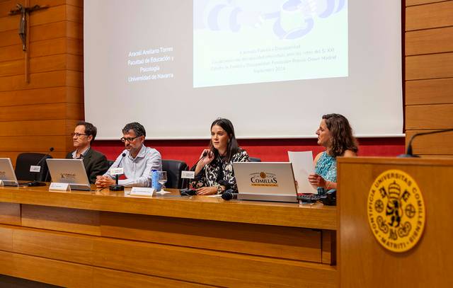 Four people sitting at a panel table in a university lecture hall during a presentation.