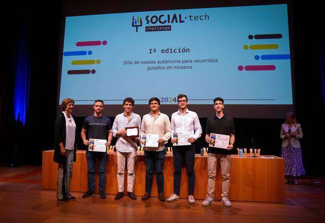 A group of people standing on stage at a social-tech event, holding certificates and smiling at the audience.