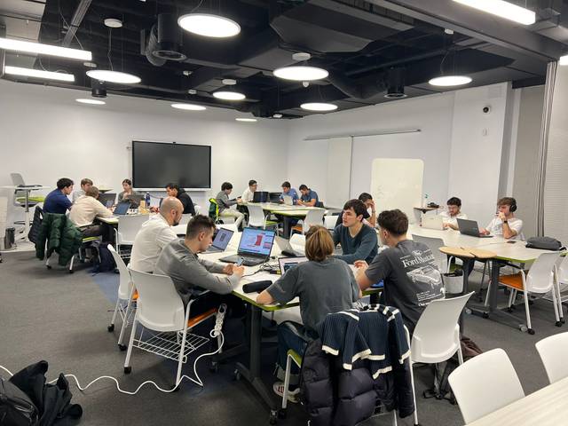 A group of people working at laptops in a modern office environment.