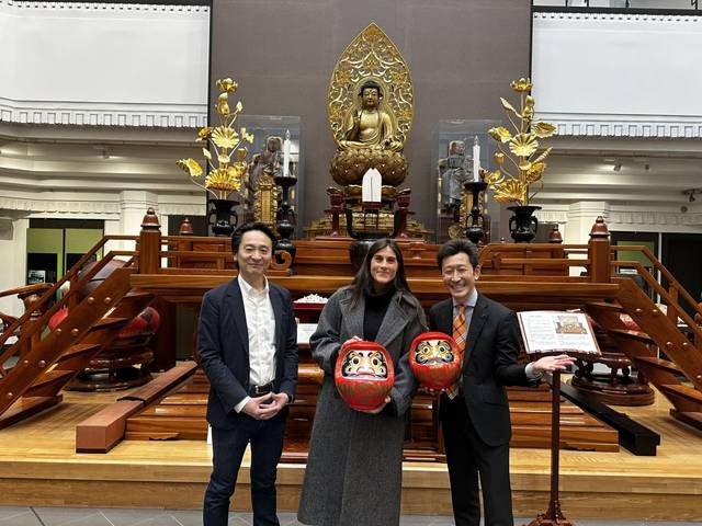 Tres personas posan frente a una estatua de Buda en un templo.