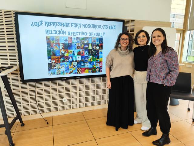 Tres personas posan frente a una pantalla que muestra una presentación sobre relaciones afectivo-sexuales.