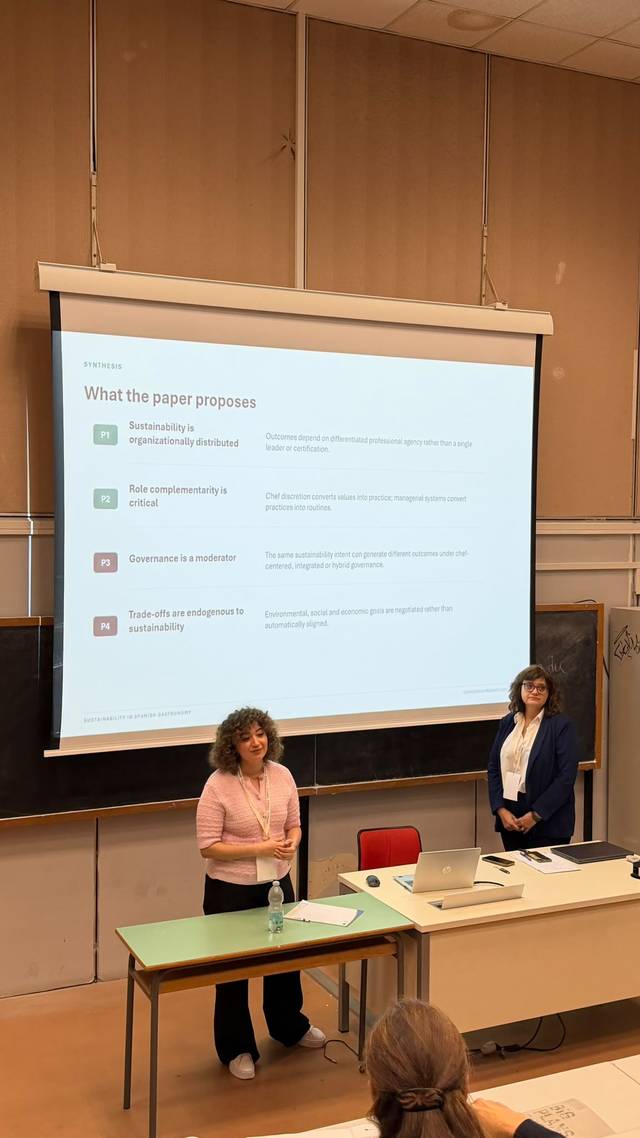 Una presentación académica en la que dos mujeres exponen información sobre un documento en una sala de clase.