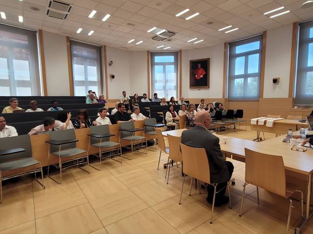 A group of people sitting in a classroom attending a presentation given by a man at the front.