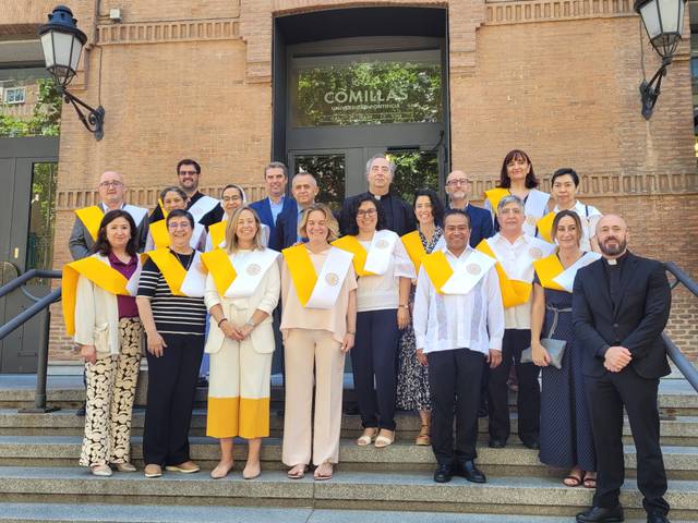 A group of people standing on steps in front of a building, some wearing graduation stoles.