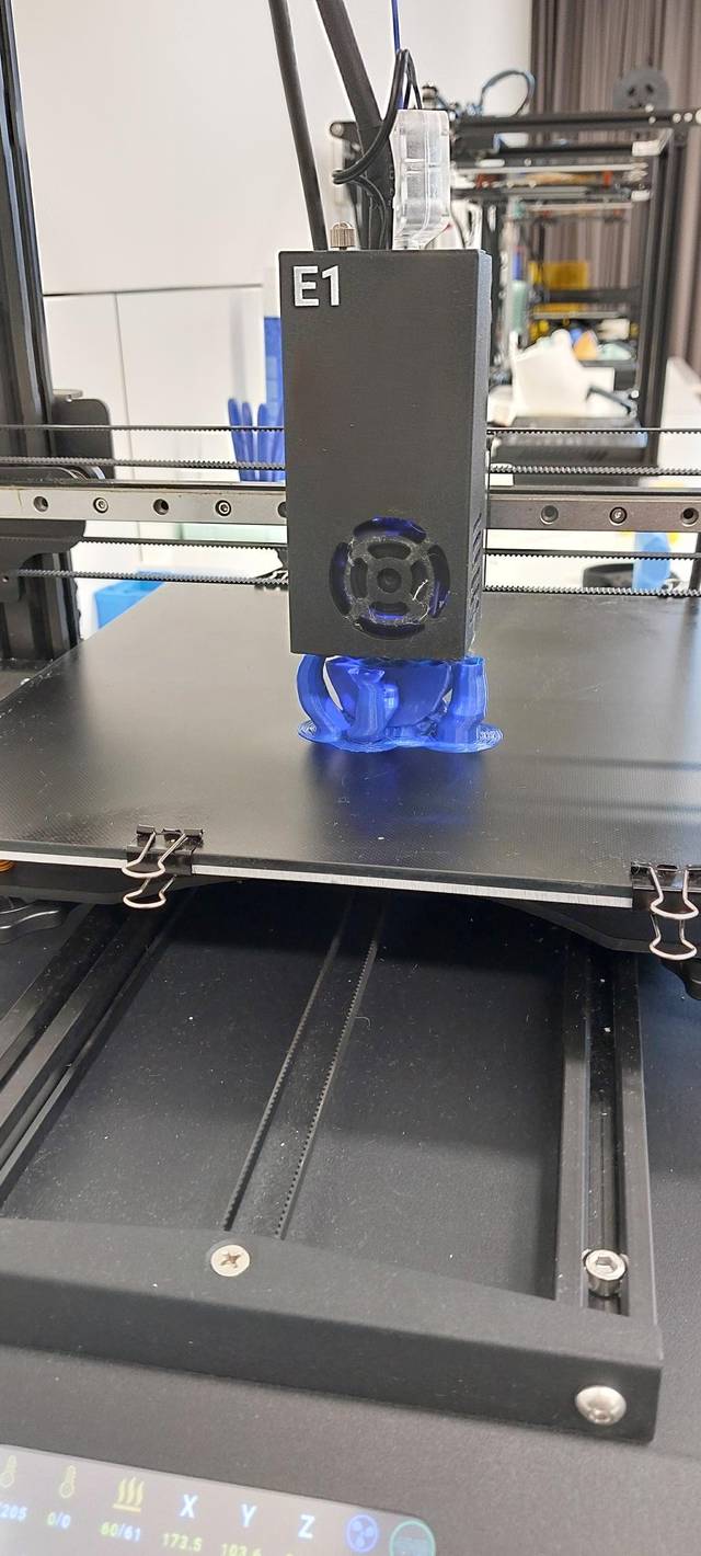 Una impresora 3D en funcionamiento con un objeto parcialmente impreso en color azul.