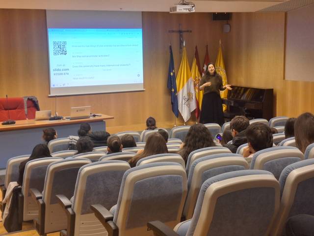 Una conferencista presenta en un auditorio frente a un público atento.