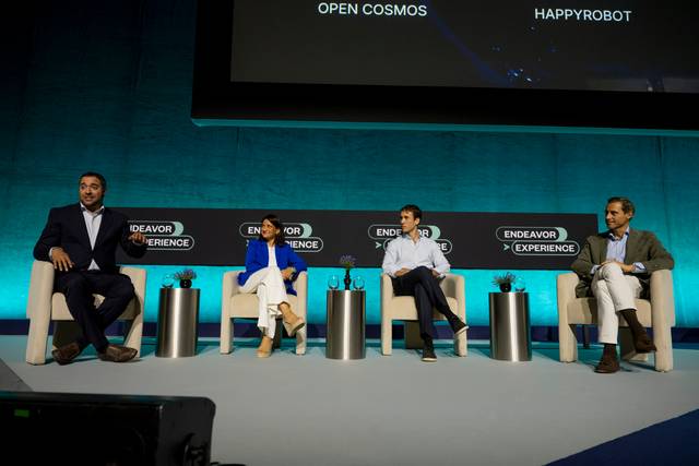 Un panel de discusión con cuatro participantes en un escenario durante un evento.