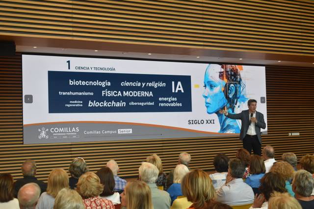 Una conferencia sobre ciencia y tecnología con un presentador frente a una pantalla que muestra conceptos relacionados como biotecnología e inteligencia artificial.