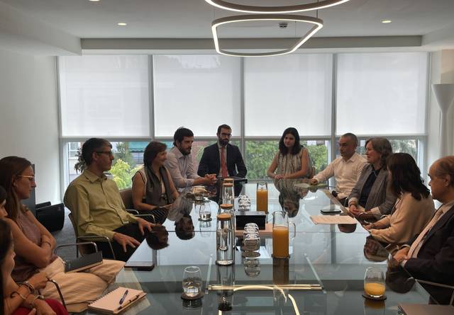 Una reunión de un grupo de profesionales alrededor de una mesa en una sala moderna.