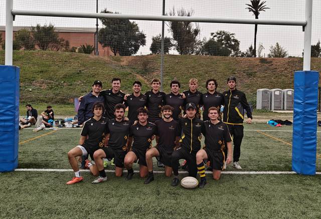 Un equipo de rugby posando frente a un arco en un campo de juego.