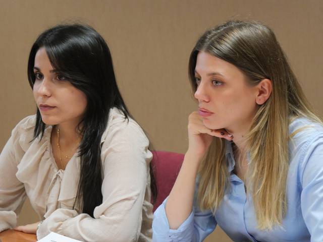 Dos mujeres observan atentamente durante una reunión.