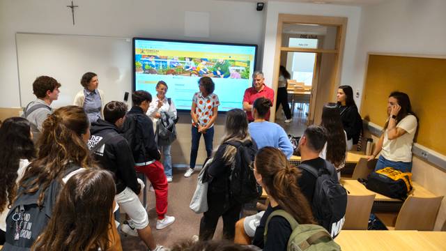 Un grupo de estudiantes escucha atentamente a un presentador en un aula.