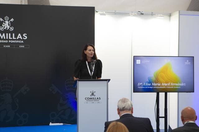 Una mujer habla en un podio ante una audiencia en un evento.