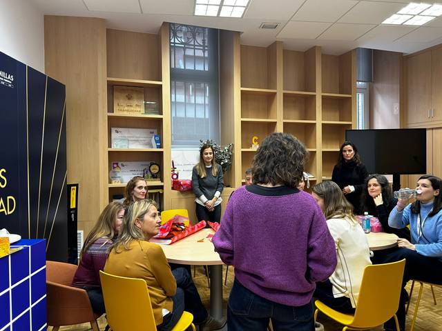 Un grupo de mujeres se reúne en una sala con estanterías, compartiendo un momento de convivencia.