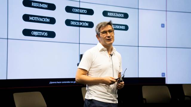 Una persona presenta en una pantalla grande con diversos encabezados relacionados con un proyecto o investigación.