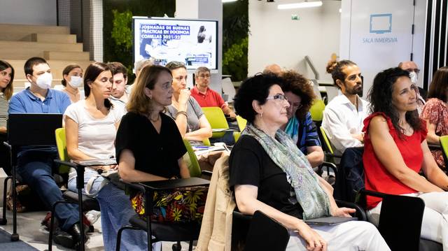 Un grupo de personas asiste a un evento, prestando atención al orador en un ambiente moderno.