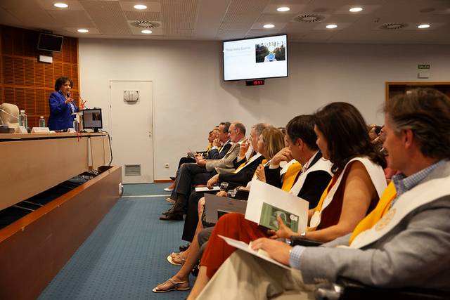 A person is giving a presentation to a group of attentive adults sitting in an auditorium.