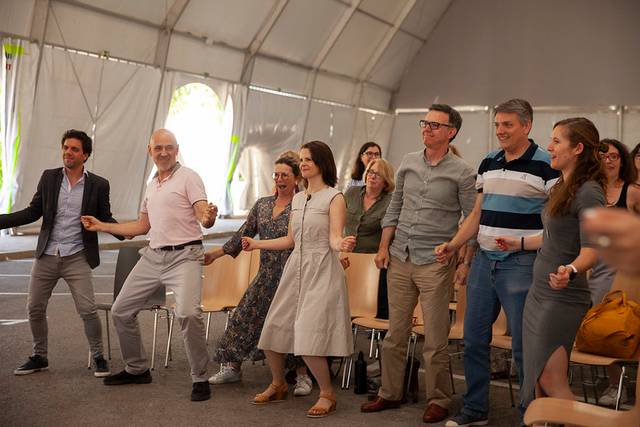 A group of adults enjoying a playful activity in a tented event space.