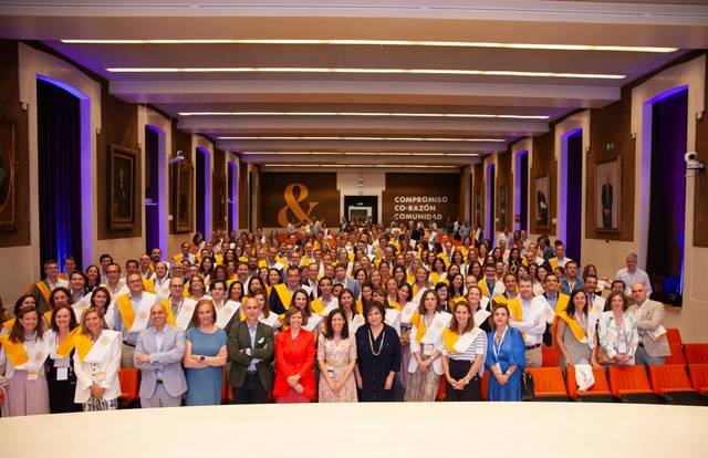 A large group of people posing for a photo in a conference hall with a banner reading 'Compromiso Corazón Comando'.